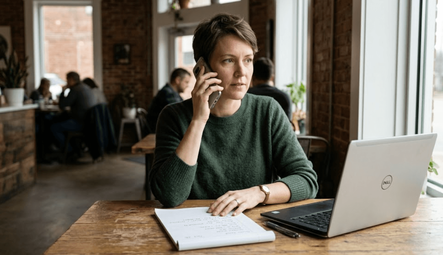 Person calling a representative, notepad nearby